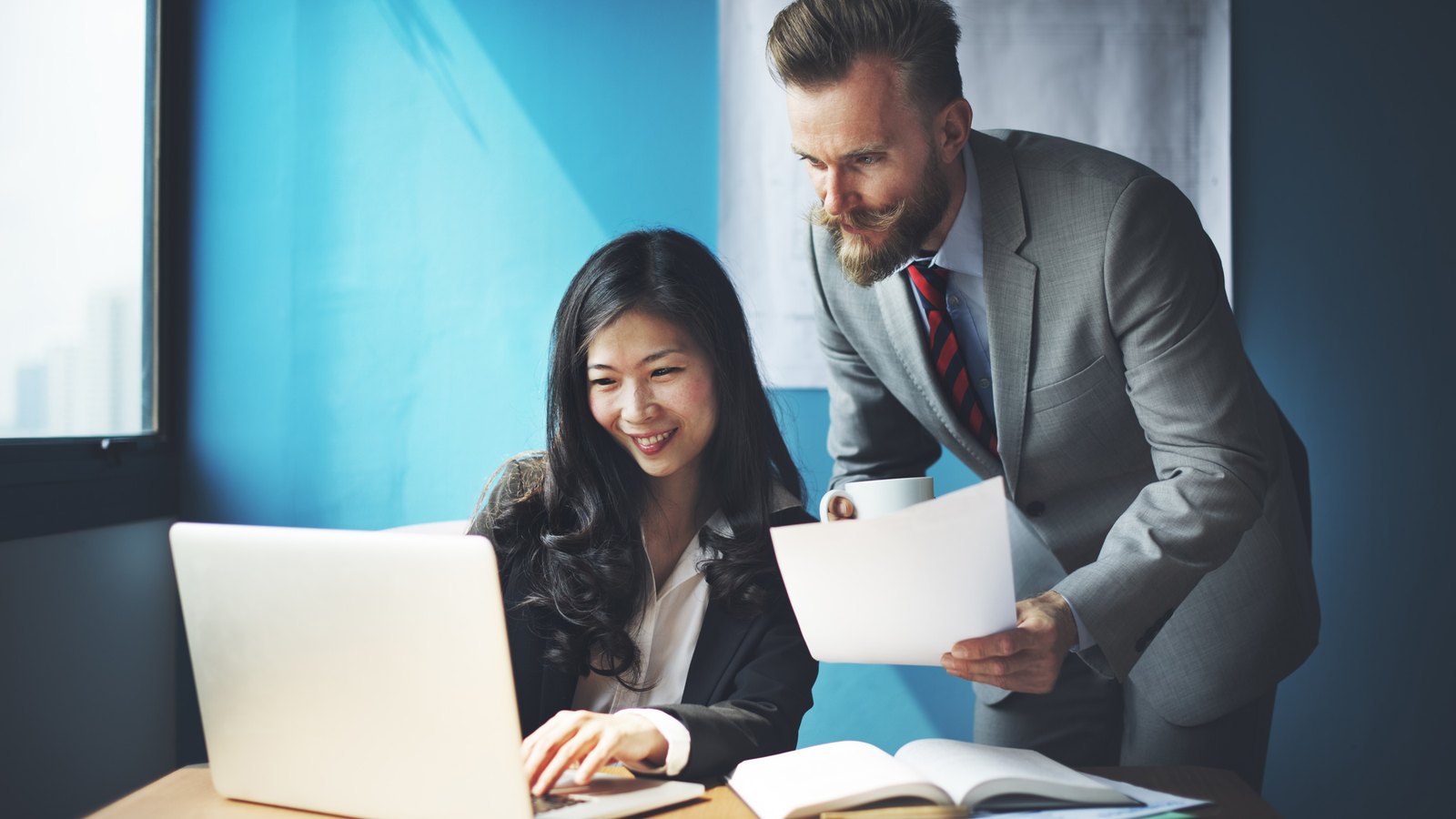 Two IT consultants reviewing a report together at a laptop